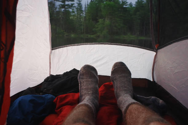 Man relaxing with Wool Socks while camping in a tent in the Adirondack mountains stock photo