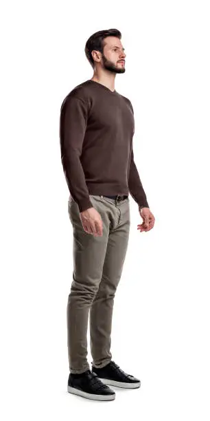 Photo of A young man in jumper and cargo pants stands looking in front in half-turned view on a white background