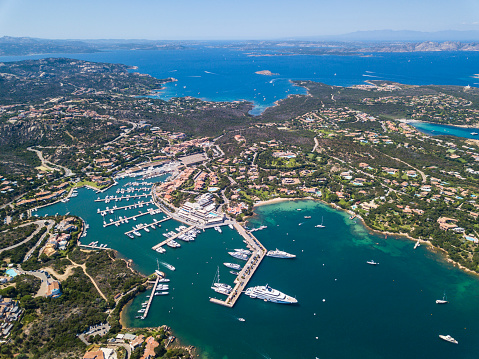 Aerial view of the village and the famous luxury marina of Porto Cervo, Sardinia, Italy. In the background the islands of La Maddalena are visible. \n\nPorto Cervo is a frazione of the comune of Arzachena, in the province of Sassari. Created by Prince Karim Aga Khan and various other investors, Porto Cervo is the main centre of Costa Smeralda. Porto Cervo is one of the most expensive resorts in the world, along as being a luxury yacht magnet and billionaires' playground.