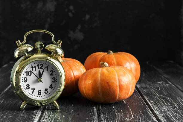 istock Pumpkins and an alarm clock on a rustic black table. Halloween time. Selective focus. 1022328940