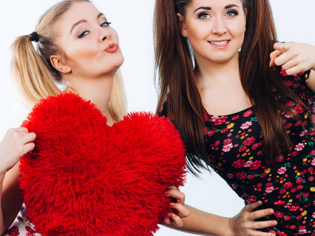 istock Happy two women holding heart shaped pillow 1022345040