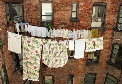 Laundry hanging on clotheslines in air shaft between NYC, New York apartment buildings