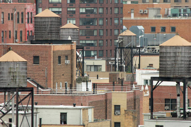 Old water tower on rooftop of building downtown New York surrounded by skyscrapers