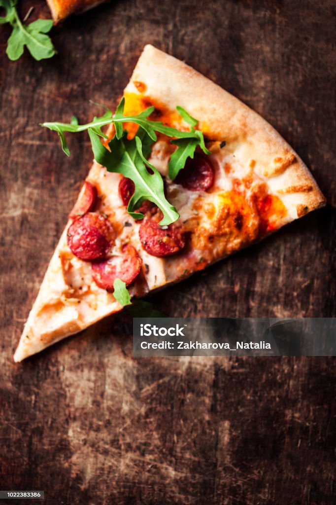 Hot pizza slice with Pepperoni, melting cheese on a rustic wooden table closeup.  Pizza Ready to Eat. Top view"n Backgrounds Stock Photo