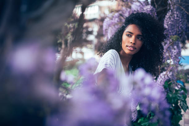 istock Young black woman sitting surrounded by flowers 1022384640