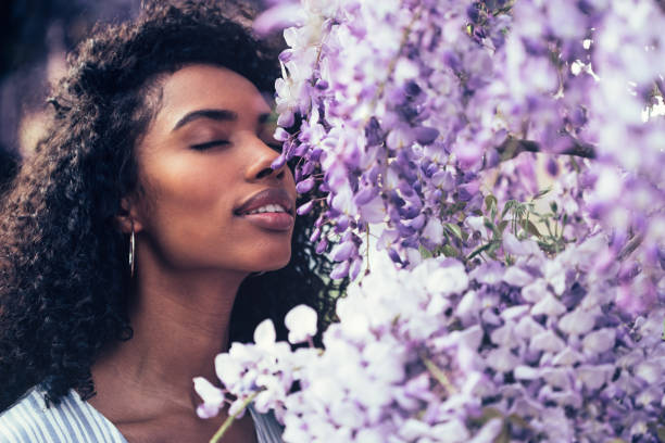 Thoughtful happy young black woman surrounded by flowers stock photo
