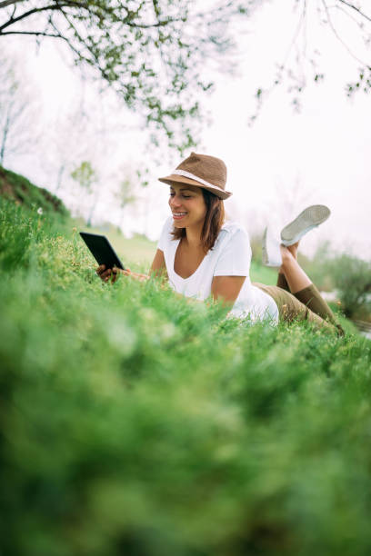 istock Woman relaxing on green grass and using tablet. 1022389080