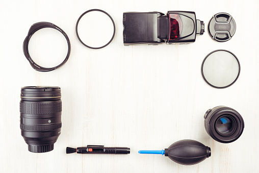 Digital camera, lenses, speedlight flash and equipment of the photographer on a wooden background. Top view, flat lay
