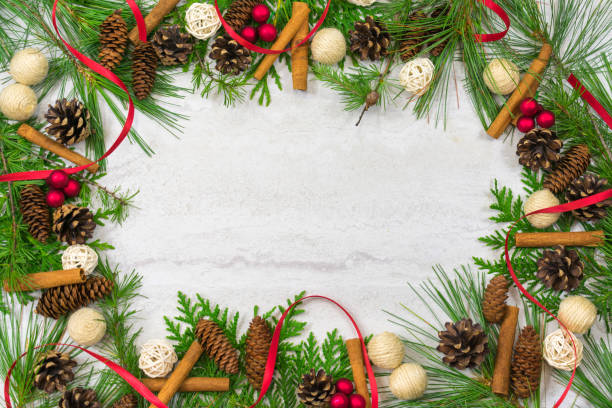 istock A border of cedar, white pine, and hemlock branches along with scotch pine. spruce, and hemlock pine cones, cinnamon sticks,twine and twig  balls,red ribbon, and berry clusters with copy space in the middle 1022397762