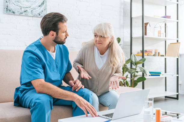 istock senior woman and young caregiver looking at each other while using laptop together 1022400664