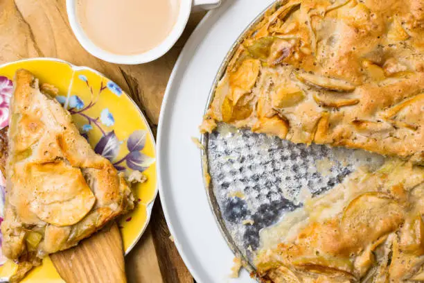 Photo of Apple crumble, Fresh baked pie and cup of coffee on the natural wood background on metal plate, closeup