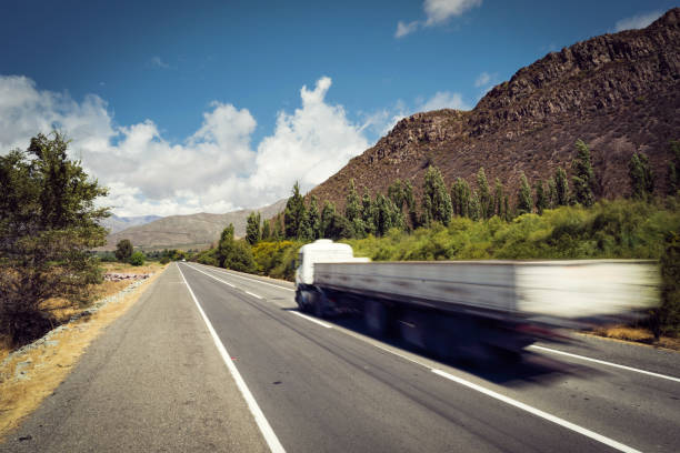 Freight truck driving fast on country road Freight truck driving in empty road with blue sky and mountain. Industry transportation, fast shipping transport. auto shipping stock pictures, royalty-free photos & images