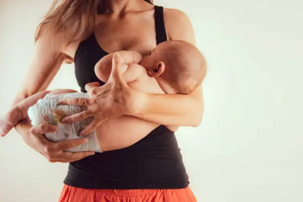 Happy mother with newborn baby infant on hands standing and breasfeeding lacting lactation health and care bonding time concept