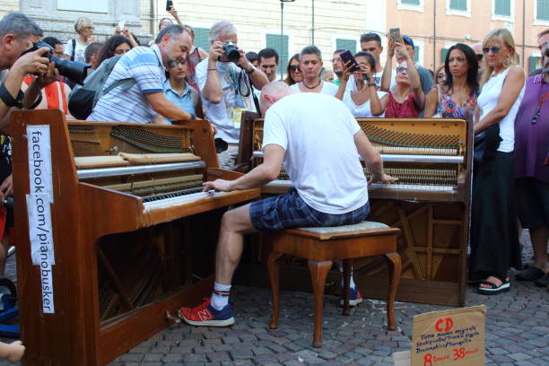 Artists perform in the street. Buskers Festival Ferrara, Italia - August 18, 2018: The Ferrara Buskers Festival is dedicated to the art of the street. Artists sing their music perform in the street. Artist perform in the street with 2 piano. Artist Piano busker contra bassoon stock pictures, royalty-free photos & images