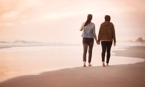 istock Lovers holding hands on a walk on the beach at sunset 1022473972