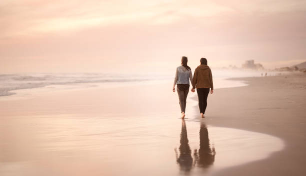 istock Lovers holding hands on a walk on the beach at sunset 1022476238