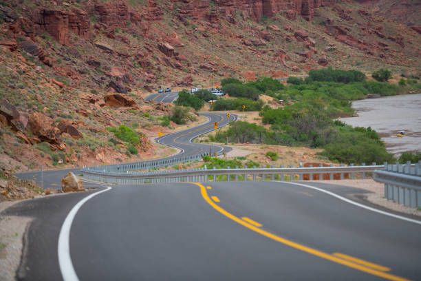 Winding Utah road, mountains and river in background