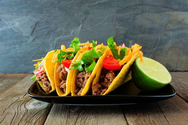 Hard shelled tacos on plate with a dark background