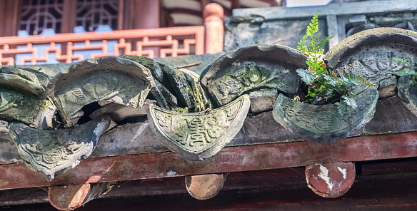 Shanghai, China - Nov 4, 2016: In Yu Yuan (Yu Garden) – A closeup view of typical Chinese roof tile traditional arrangement pattern. Fern growing in crevice.