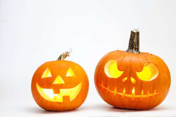 Two Halloween pumpkin head jack lantern with burning candles isolated on white background stock photo