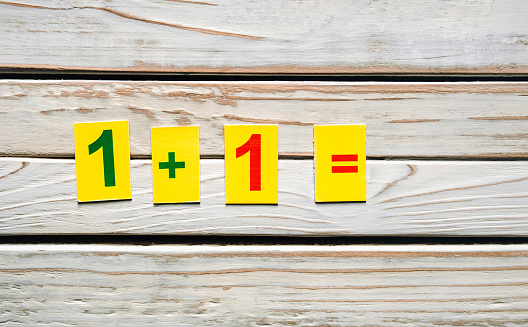 One plus one concept. Mathematics. School knowledge. Primary School. Digits on a wooden background. Education.