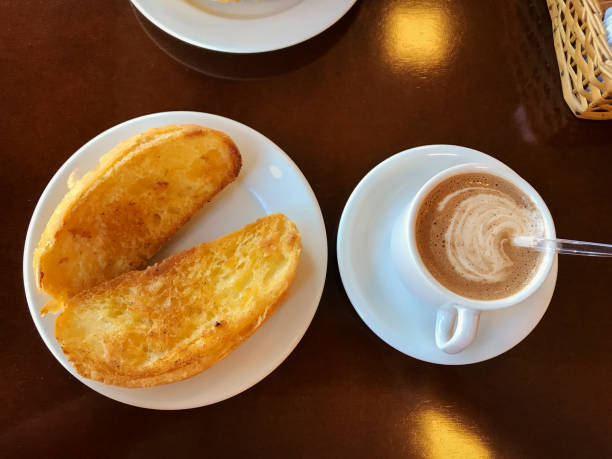 Breakfast at Brazil with french bread toasted with butter on the plate with capuccino on table. stock photo