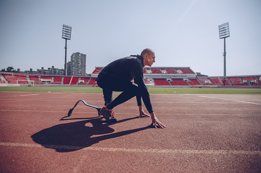 One man, athlete with amputee leg and prosthetic leg sprinter on sports track.