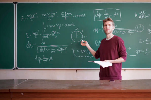 young professor teacher with microphone standing near the blackboard and speaking on the university lection - physics classroom teaching professor imagens e fotografias de stock