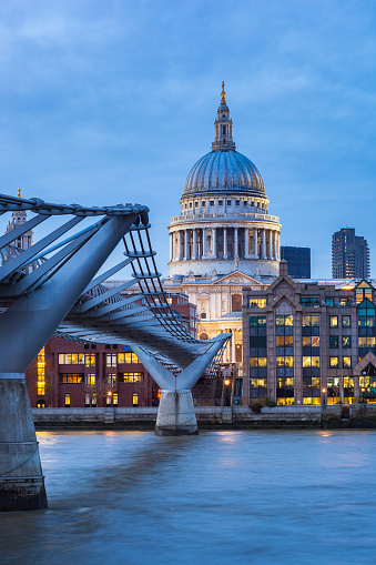 Stock photograph of the Millennium Bridge and St Pauls Cathedral in downtown London England UK at twilight blue hour.