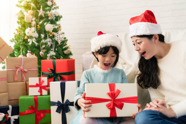 niña abre el regalo con su madre - blinding fotografías e imágenes de stock