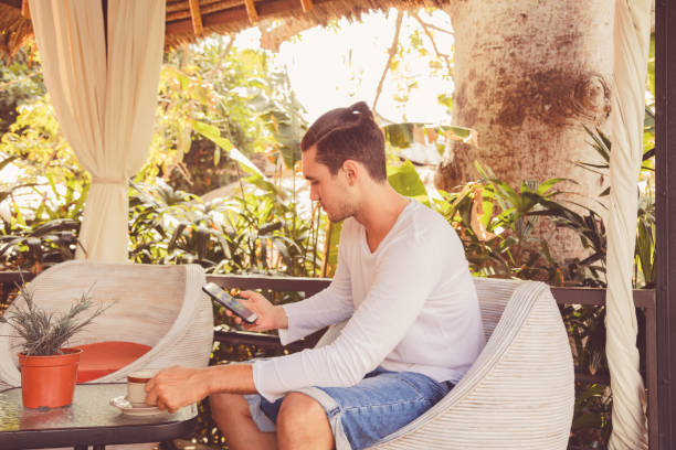 istock Attractive man using cellphone and drinking coffee outdoors. 1022639028