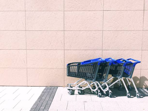 A row of blue shopping trolleys or carts outside a large department store wall with copy space