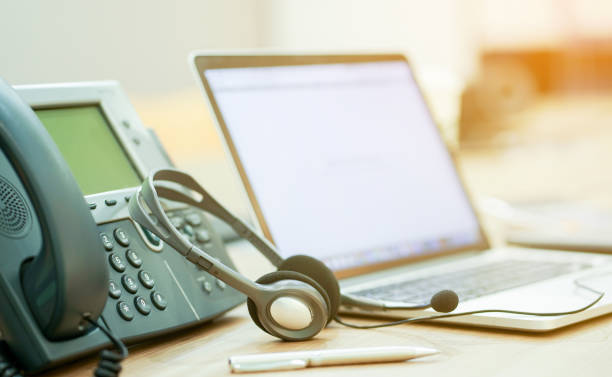 istock close up focus on call center headset device at telephone VOIP system at office desk for hotline telemarketing concept with vintage color filter 1022715134