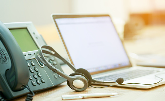 close up focus on call center headset device at telephone VOIP system at office desk for hotline telemarketing concept with vintage color filter