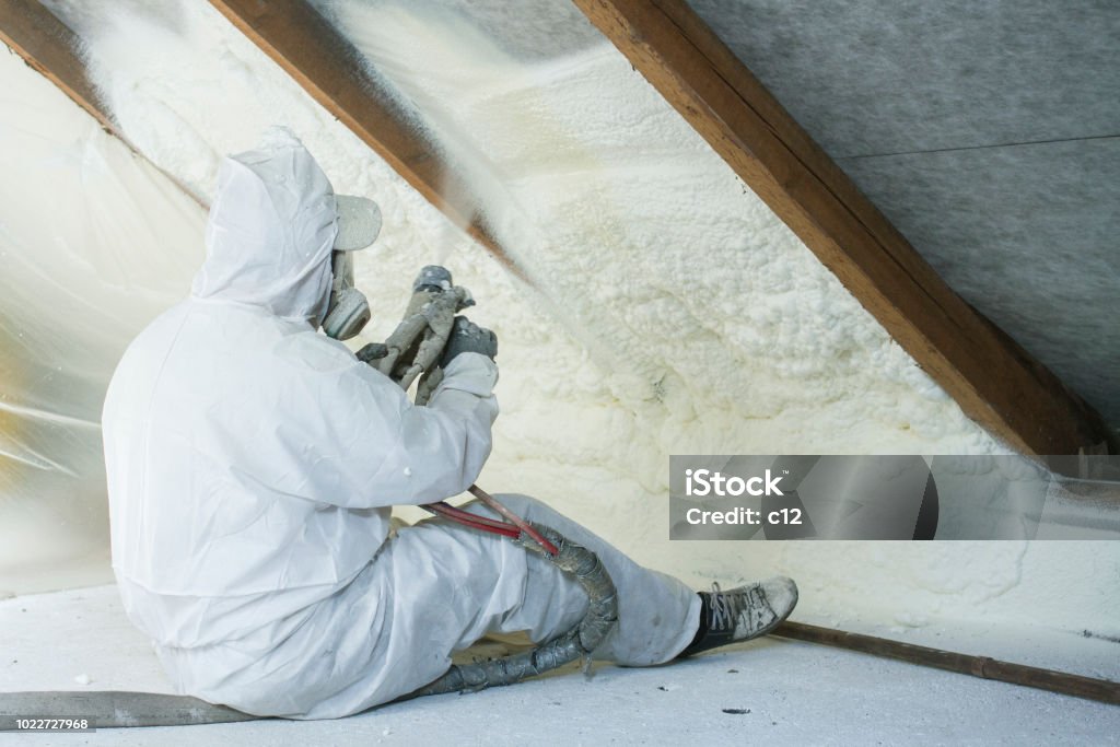 spray polyurethane foam for roof spray polyurethane foam for roof - technician spraying foam insulation using plural component gun for polyurethane foam, inside Insulation Stock Photo