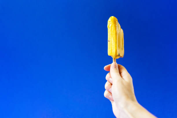 istock Bright yellow ice cream in girl's hand on a deep blue background. 1022730156