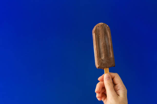 istock Girl's hand with chocolate ice cream on deep blue background. 1022730368
