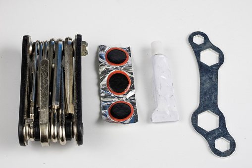 Bicycle tube, glue and patches in the workshop. Repairing a damaged wheel in a bike. Light background.