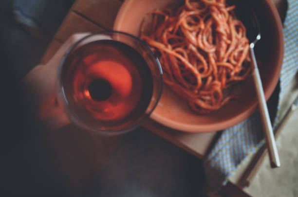 Pasta with tomatoes and glass of red wine in hand, selective focus