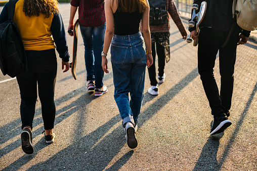 Vista posterior del grupo de amigos de la escuela caminando al aire libre estilo de vida photo