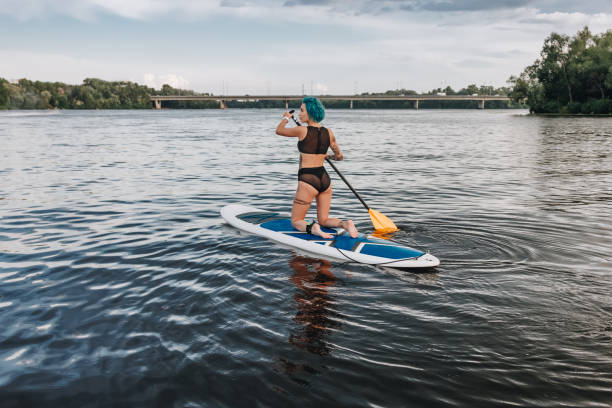 istock beautiful athletic tattooed woman in bikini paddle boarding on river 1022749134