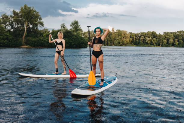 istock athletic tattooed women standup paddleboarding on river 1022749148