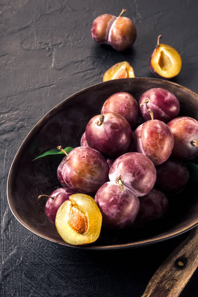istock Whole fresh red violet blue plums and slices cut with knife in bowl on kitchen table 1022754010