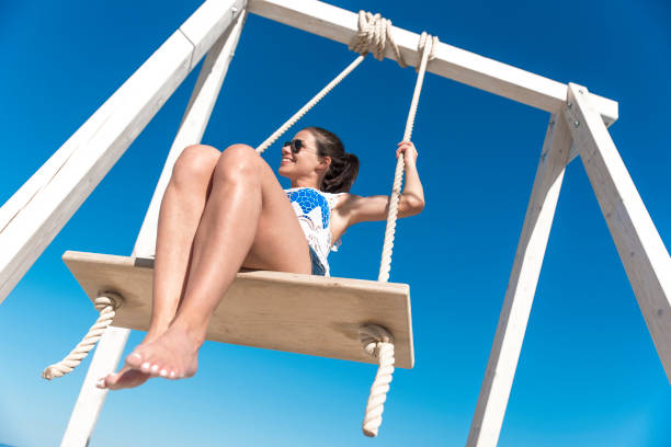 istock Young woman swinging outdoors on a white swing 1022770222