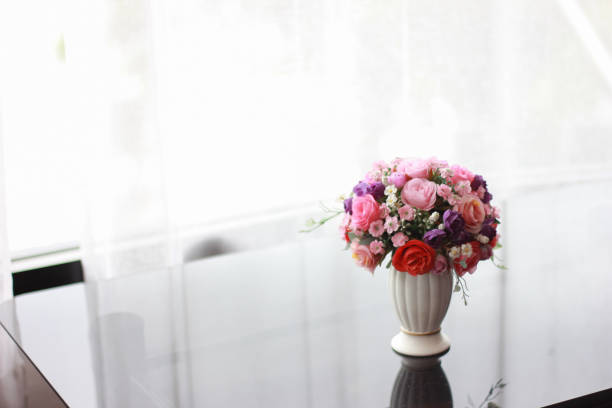 One rose bouquet on glass table with curtain background.