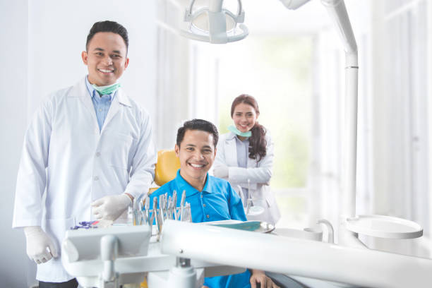 стоматолог улыбается с пациентом мужского пола в стоматологической клинике - dentist asian ethnicity portrait male стоковые фото и изображения