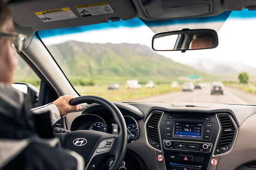 Utah, USA - A view of a man driving a Hyundai SUV on a rural freeway, with light daytime traffic on the road ahead.