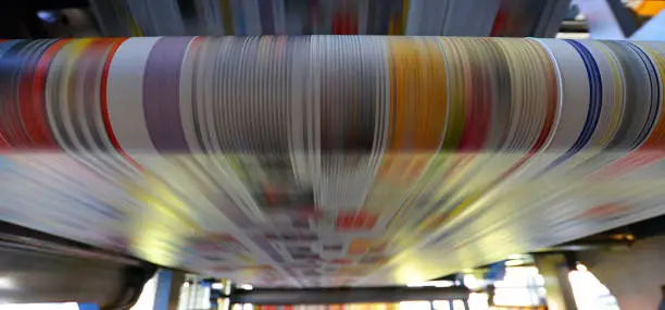 Photo of printing of coloured newspapers with an offset printing machine at a printing press