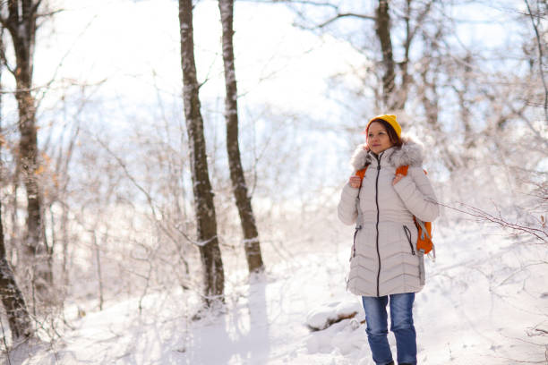 istock Woman with a backpack walking through winter forest 1022819874