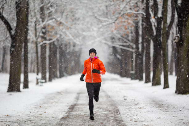 istock happy woman jogging training during snowfall on cold winter day in empty avenue 1022820044